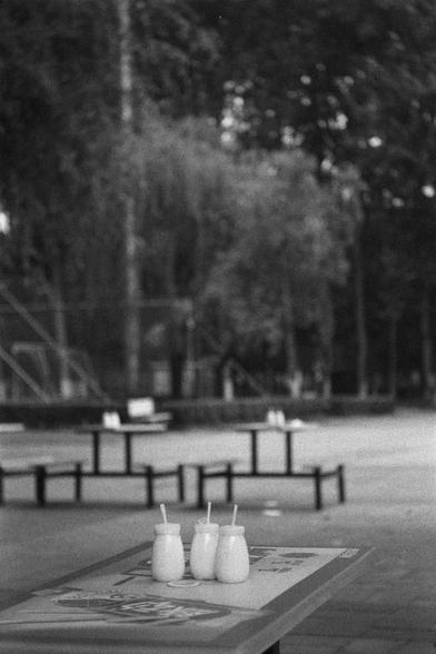 Ilford HP5 Plus 400 (FF)

English
A black and white photograph of a park scenery. A few tables with benches can be seen. Some glass bottles with straws are on the table in the foreground. The background is blurry and covered with dense foliage of trees.

中文
一張黑白照片.照片的公園場景中,有一些桌椅.前景中的桌子上有一些玻璃瓶,瓶中有吸管.背景模糊,可以明確的看到植被的覆蓋.