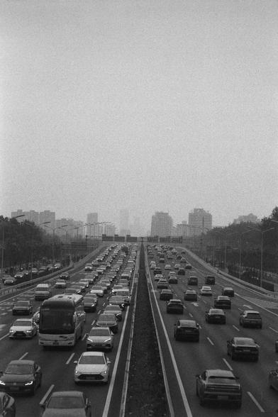 Ilford HP5 Plus 400 (FF)

English 
A black and white photograph of a busy highway. Traffic is lining up, more on the left side. An urban skyline can be vaguely seen in the background.

中文
一張黑白照片.照片中是一個繁忙的公路.左側的車流略大於右側.背景中隱約可見城市的天際線.