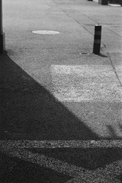 Ilford HP5 Plus 400 (FF)

English
A black and white photograph. A metal stand is on the ground to the top right of the photo in the light. The shade covers the bottom left area of the photo.

中文
一张黑白照片.一个金属桩子立在照片的右上角.桩子在阳光里.右下角在阴影中.