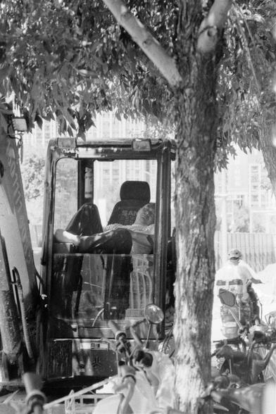 Lucky LUCKY SHD 400 (FF)

English
A black and white photograph. At the center of the photo, the driver of a heavy machine is sleeping in the operating room, under the leaves of a tree. The background is lit. People and buildings can be seen.

中文
一张黑白照片.照片中一辆叉车停在树阴下.司机在驾驶室中睡着.背景很亮,可以看见人和高楼.