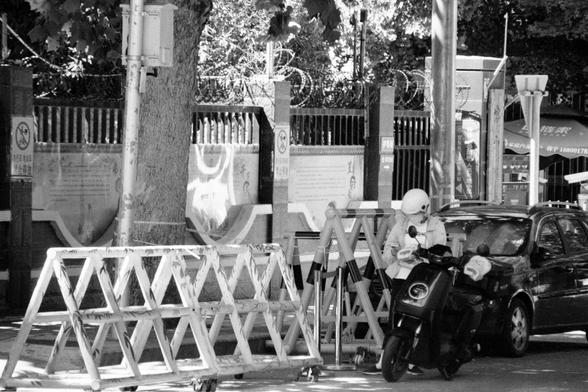Lucky LUCKY SHD 400 (FF)

English
A black and white photograph. A person stands on the side of a motorcycle parked by the street. The person leans against a barricade on the right side of a car. Trees can be seen planted inside a wall along the pedestrian lane.

中文
一张黑白照片.照片中一个人站在一辆摩托车旁. 这个人靠在一辆汽车右边的路障上.人行道边的墙内栽种了树木.